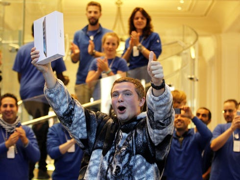 The first customer to purchase an iPad Air exits an Apple Store in Amsterdam.