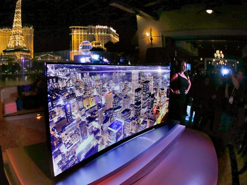 A model stands next to a Samsung 105-inch UHD curved TV during a preview event for the International Consumer Electronics Show in Las Vegas.