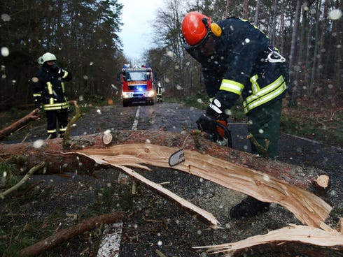 Firefighters cut a tree with a chain saw to clear the street after a Dec. 6 storm in Graal-Mueritz,��Germany.