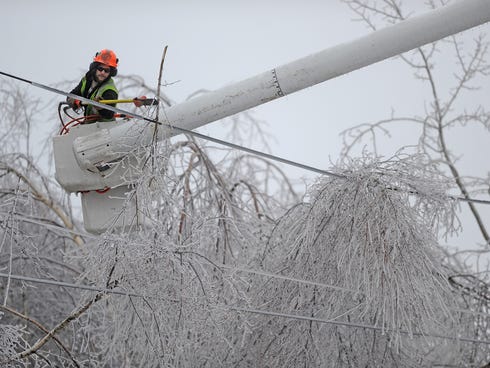 Andrew Powers, an arborist with Asplundh Tree Experts, clears iced branches from power lines along Mayflower Heights Drive in Waterville, Maine, on Dec. 23, 2013.