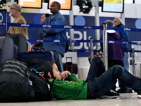 Seven-year-old Jordan Knowles rests his head against his family's luggage. They were rebooking their JetBlue flight back home to the Bahamas at Boston's Logan Airport on Monday, when JetBlue halted operations in Boston, New York and New Jersey due to