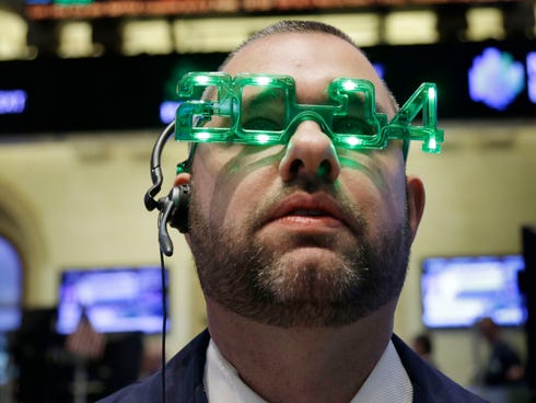 A trader wears glasses celebrating the new year while working on the floor at the New York Stock Exchange in New York, Tuesday, Dec. 31, 2013.