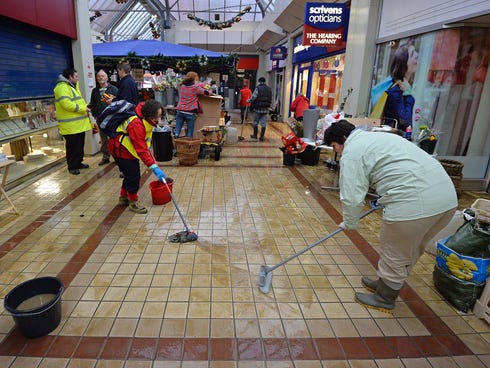 People mop the floor at the Angel Centre retail centre in Tonbridge in south-east England, on December 27, 2013, following recent floods.