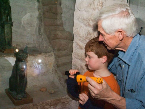 A grandfather and grandson explore the Field Museum's Inside Ancient Egypt exhibit on a flashlight tour as part of a family overnight at the museum.