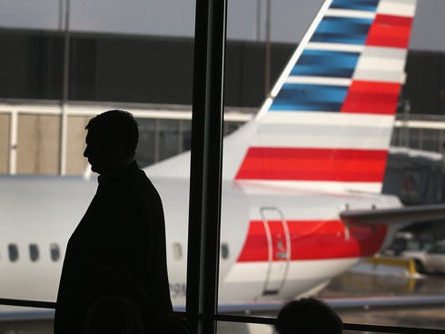 An American Airlines jet with the company's new tail logo sits at a gate at Chicago's O'Hare Airport Dec. 9.  American has completed a merger deal with US Airways. The deal will make American Airlines the world's largest airline, flying about 6,700 f