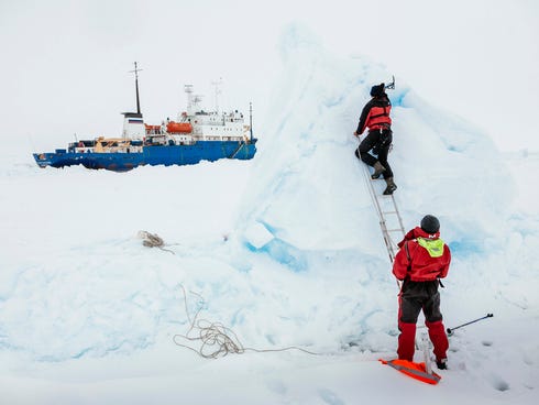 In this Dec. 31, 2013, image provided by Australasian Antarctic Expedition/Footloose Fotography, Ben Maddison and Ben Fisk from the Russian ship MV Akademik Shokalskiy work to place a wind indicator atop an ice feature near the trapped ship 1,500 nau