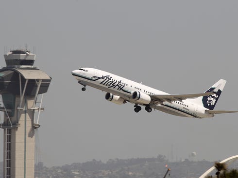 An Alaska Airlines jet passes the air traffic control tower at Los Angles International Airport (LAX) on April 22, 2013.