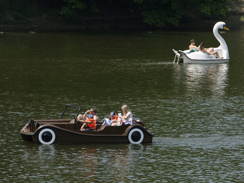 Tourists enjoy a sunny day as they cruise the Vltava River in a pedal boat near the famous Charles bridge in Prague, Czech Republic.