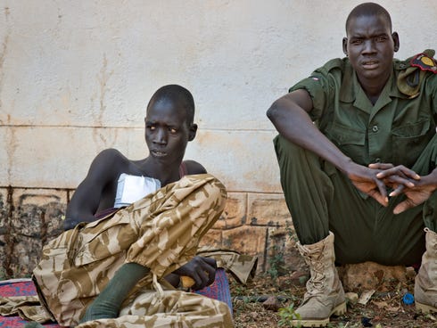 A wounded soldier sits with a colleague in an outside courtyard at the Juba Military Hospital in Juba, South Sudan on Dec. 28, 2013. A spokesman for South Sudan's military says fighting continues in the oil-producing Unity state despite ongoing effor