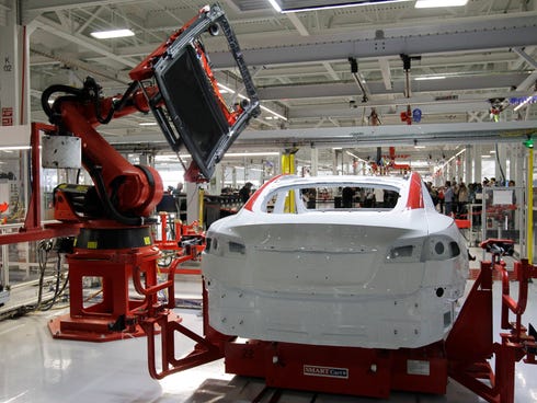 A robot puts on the top of a Tesla Model S at the Tesla factory in Fremont, Calif.