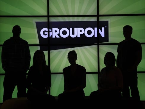 Employees at Groupon pose in silhouette by the company logo in the lobby of the online coupon company's Chicago offices.