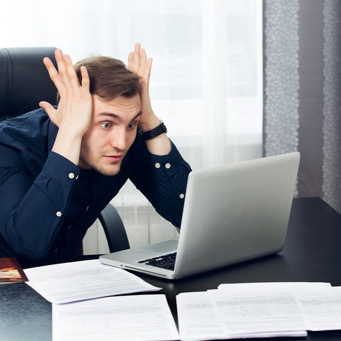 A young office worker leans both elbows on his des