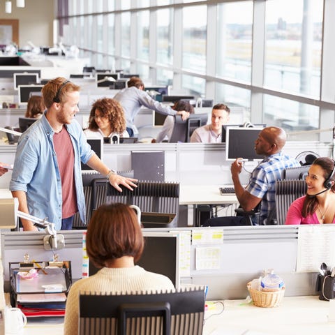 Bustling office, with people sitting at computers 