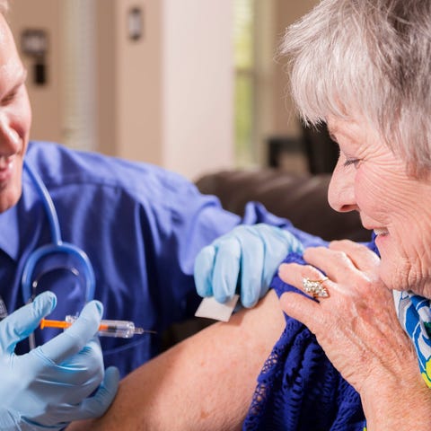 A physician administering a vaccine to an elderly 