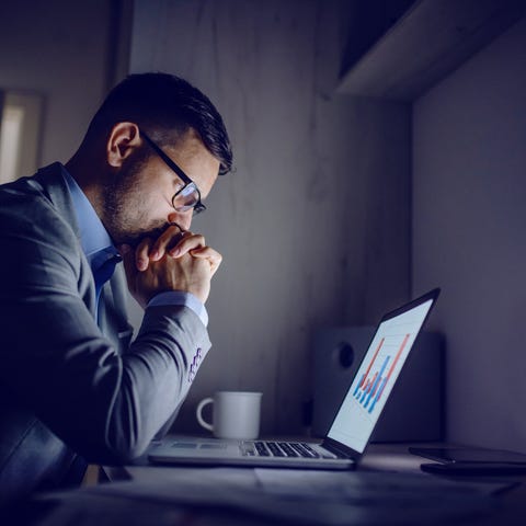 Man with serious expression staring at graph on la