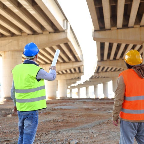 two construction workers look at the underside of 