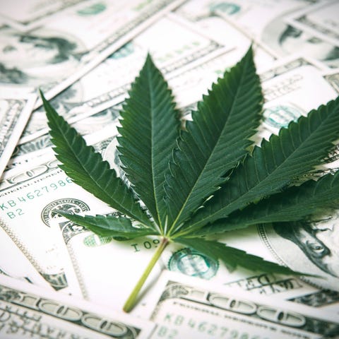 Marijuana leaf on a stack of $100 bills.