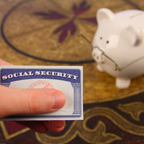 A hand holding a Social Security card next to a wh