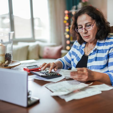 Senior with calculator and laptop reviewing papers