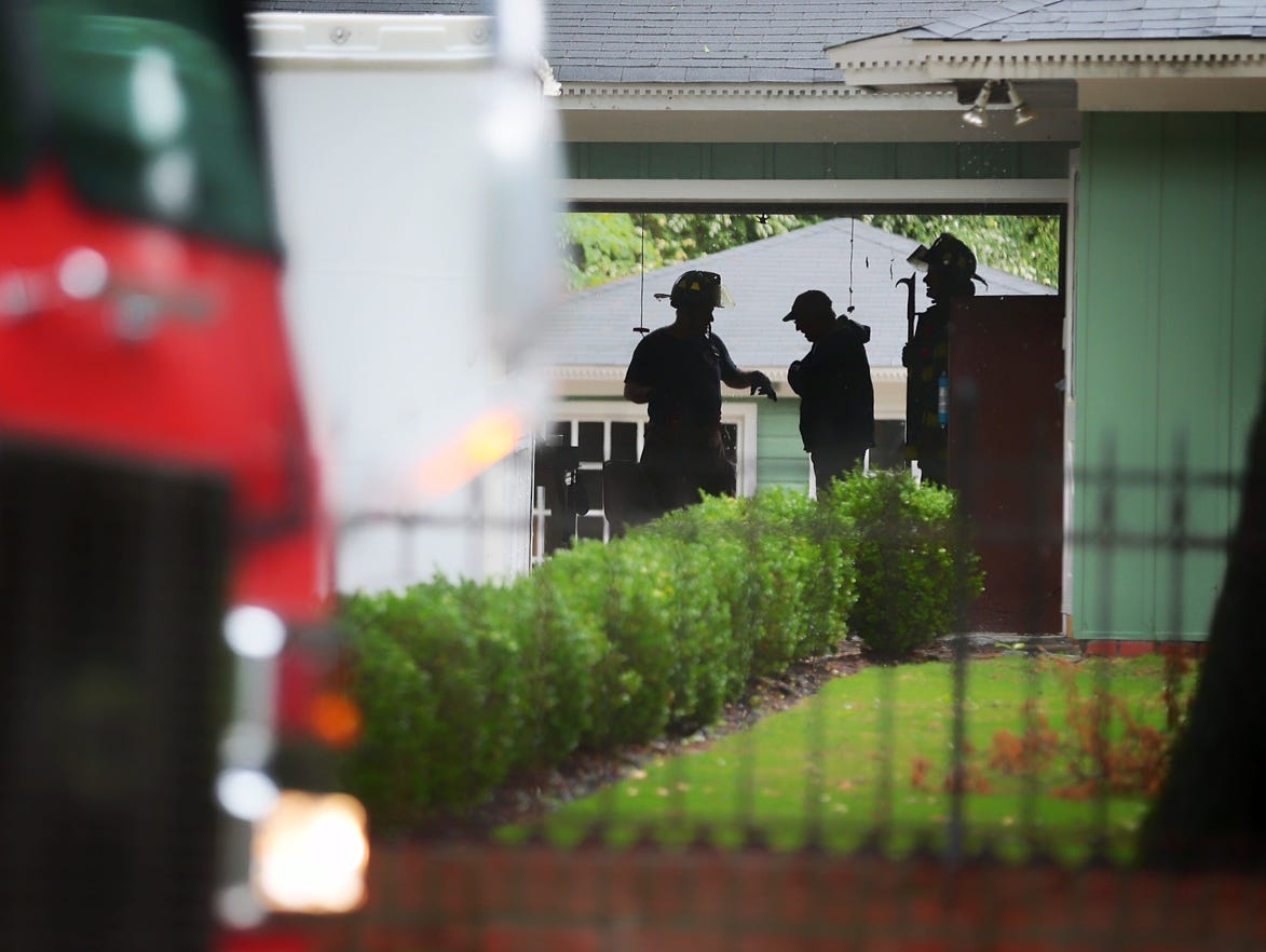 Memphis firefighters gather under the carport at the former home of Elvis Presley after a fire Saturday morning damaged the historic structure on Audubon Drive.