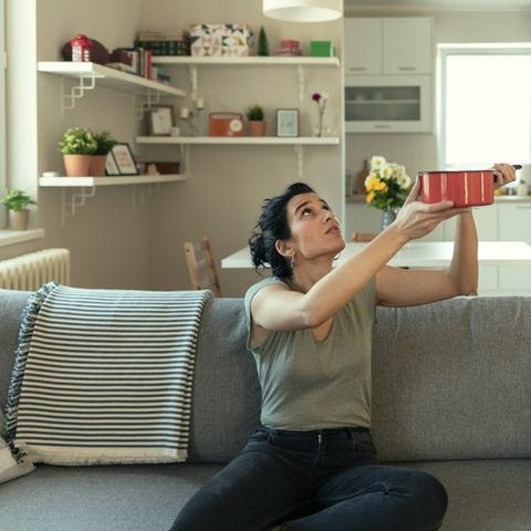 A woman sitting on her couch and holding up a pot 