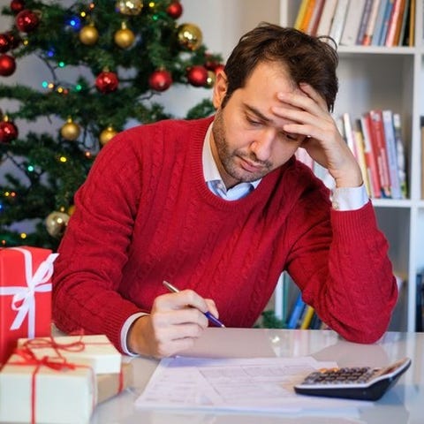 A man looks at bills beside a stack of presents.