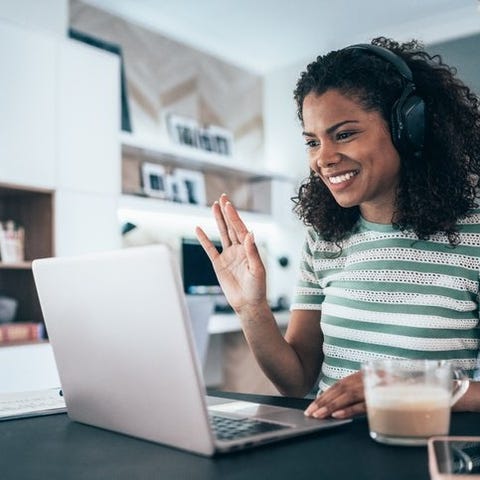 A woman works from home as she smiles and waves to