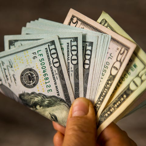 A person holding a folded assortment of cash bills