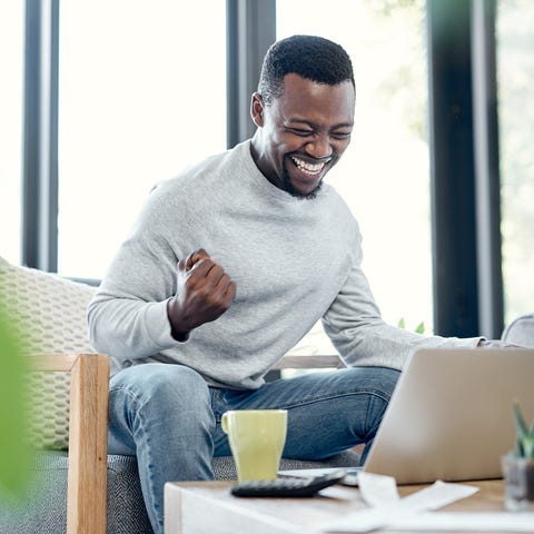 Smiling person fist-pumps in front of a computer a