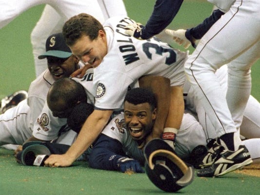 FILE - In this Oct. 8, 1995, Seattle Mariners photo file 'Ken Griffey Jr. smiles from beneath to pile of teammates who mobbed him after he scored the winning run in the bottom of the 11th inning of a baseball game against the New York Yankees in Seattle. Ken Griffey Jr. seems assured of election to the Baseball Hall of Fame Wednesday, Jan. 6, 2016, possibly with a record vote of close to 100 percent. Mike Piazza, Jeff Bagwell and Tim Raines also were strong candidates for winning the 75 percent needed for baseball's highest honor. (AP Photo / Elaine Thompson, File)