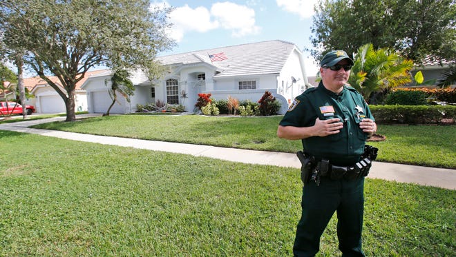 A Palm Beach County Sheriff's deputy keeps watch over the home of Palm Beach Gardens police Officer Nouman Raja, Wednesday, Oct. 21, 2015, in Lake Worth, Fla.