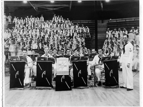 Members of the USS Arizona dance band pause at Bloch Arena, Pearl Harbor, during the Battle of Music semifinal held Nov. 22, 1941. From left, they are Musician 2nd Class Curtis Haas, Musician 2nd Class Gerald Cox, Musician 2nd Class Ernest Whitson Jr., Musician 2nd Class Frank Floege, Musician 2nd Class Clyde Williams, Musician 2nd Class Bernard Hughes, Musician 2nd Class Alexander Nadel, Musician 2nd Class Charles White, Musician 2nd Class Robert Shaw, Musician 2nd Class Harry Chermucha, Musician 2nd Class William Moorhouse, Musician 2nd Class Emmett Lynch, Musician 2nd Class Wayne Bandy, Musician 2nd Class Jack Scruggs, Musician 2nd Class James Sanderson, and Musician 1st Class Frederick Kinney. (Photo: Official U.S. Navy photo)