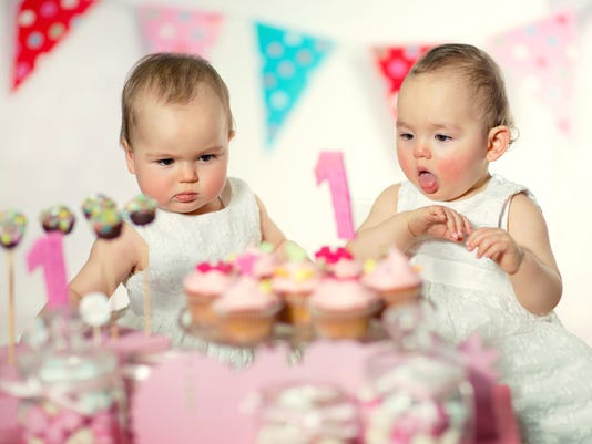 Beautiful happy twins baby on first birthday background.
