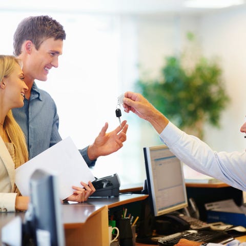 An employee hands keys over to a customer who is r