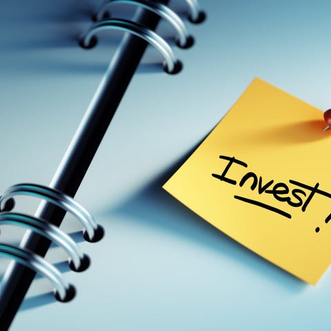 A post-It note saying "invest!" is pinned to the p