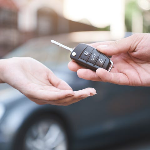 A person hands off a car key to another person.