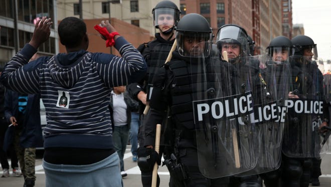 A protester holds up his hands as police in riot gear pass through ...