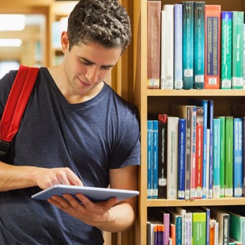 Young male wearing a backpack using a tablet...