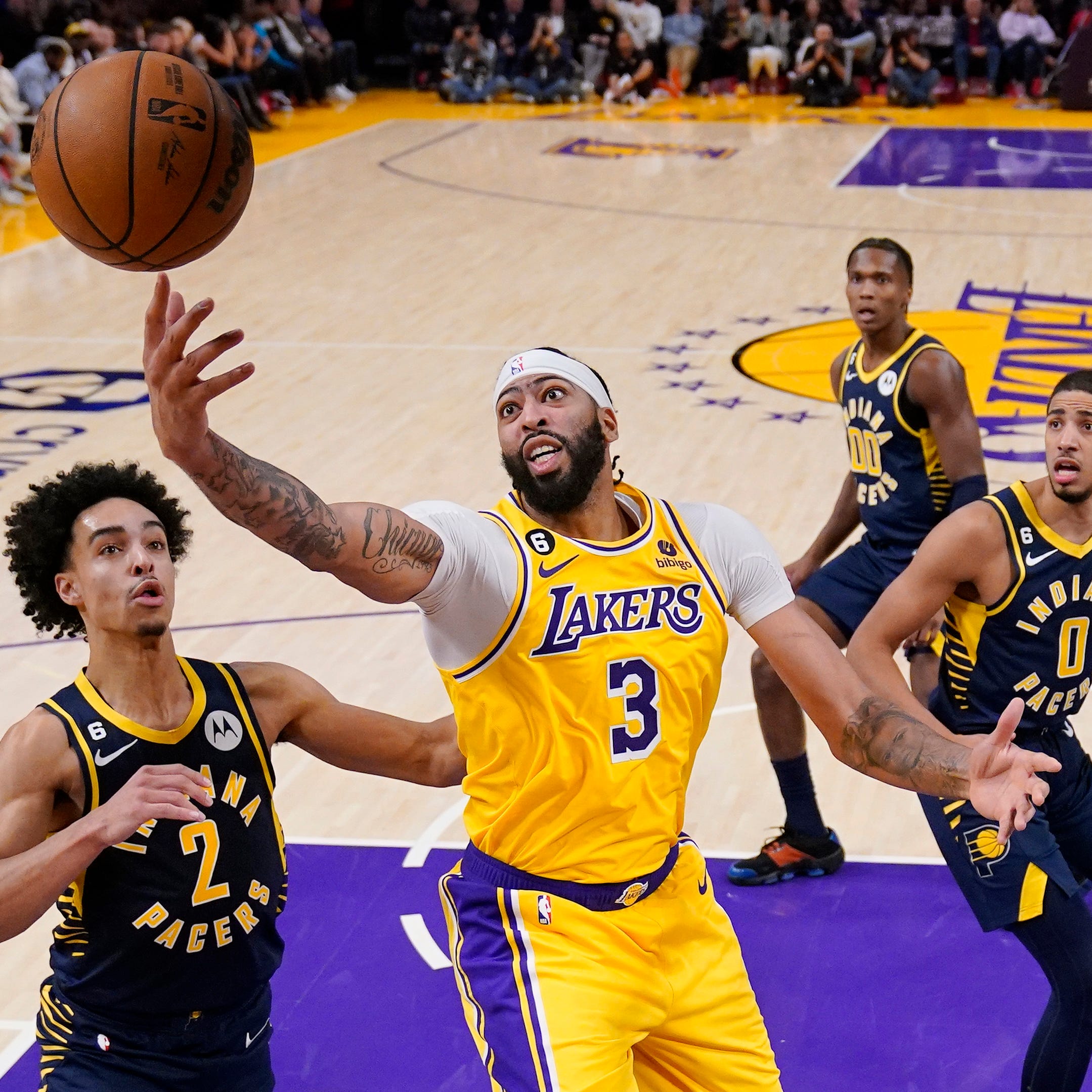 Los Angeles Lakers forward Anthony Davis, second from left, reaches for a rebound as Indiana Pacers guard Andrew Nembhard, left, guard Bennedict Mathurin, second from right, and guard Tyrese Haliburton watch during the second half of an NBA basketball game Monday, Nov. 28, 2022, in Los Angeles. (AP Photo/Mark J. Terrill)