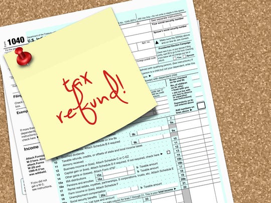 A yellow sticky note reading tax refund is tacked to tax form 1040