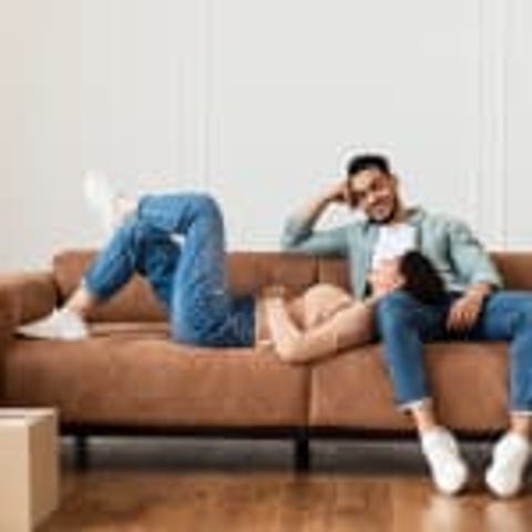 A couple lounging on a couch surrounded by moving 