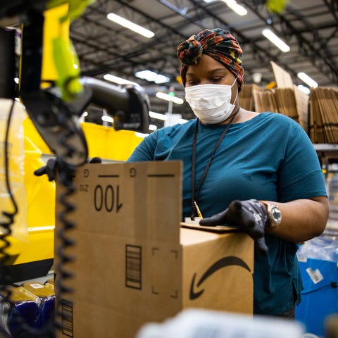 Amazon worker in a warehouse closing up a box for 