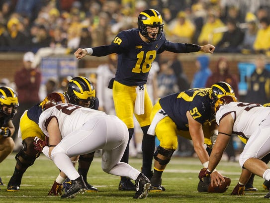 Michigan quarterback Brandon Peters (18) talks to teammates