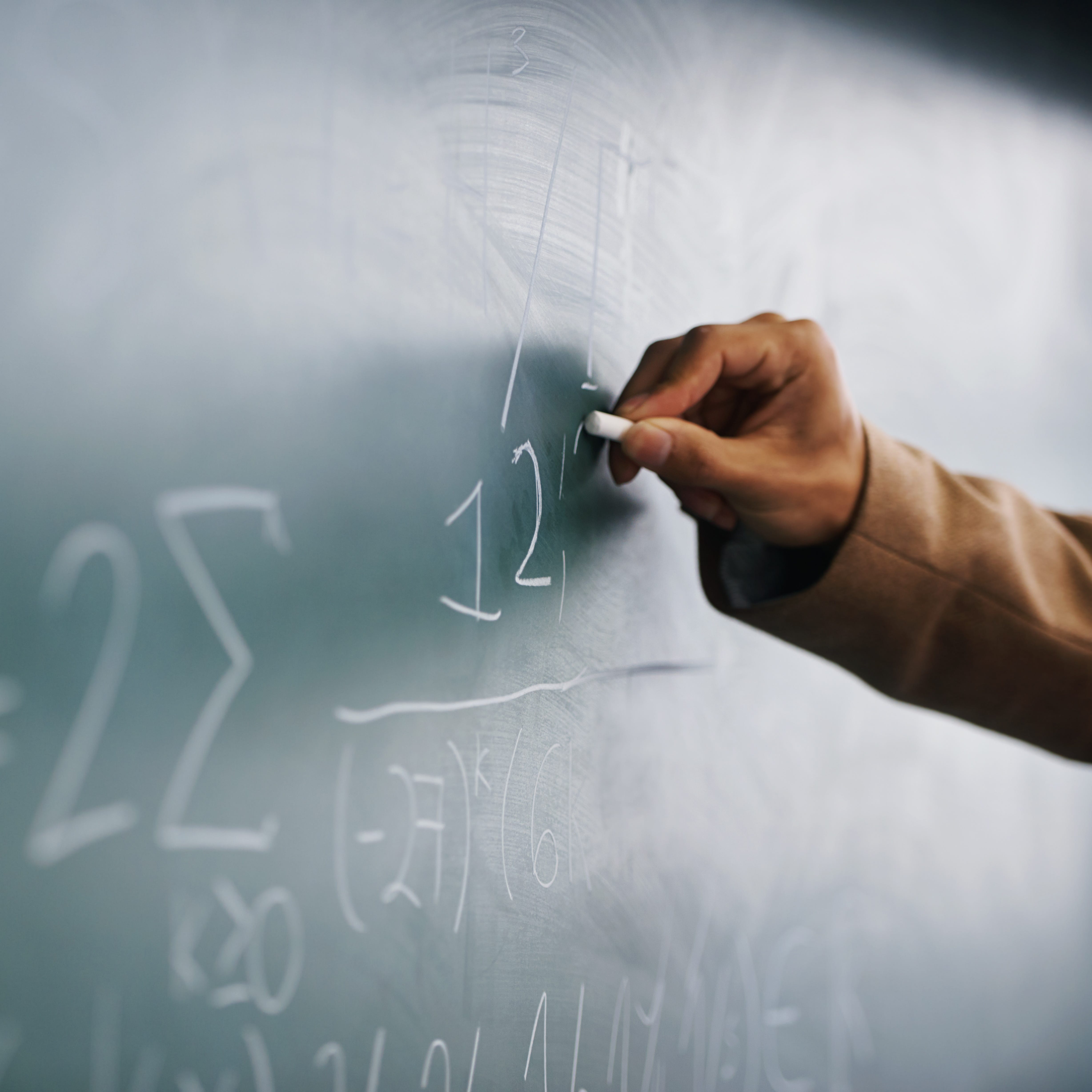 Teacher writing a formula on a blackboard