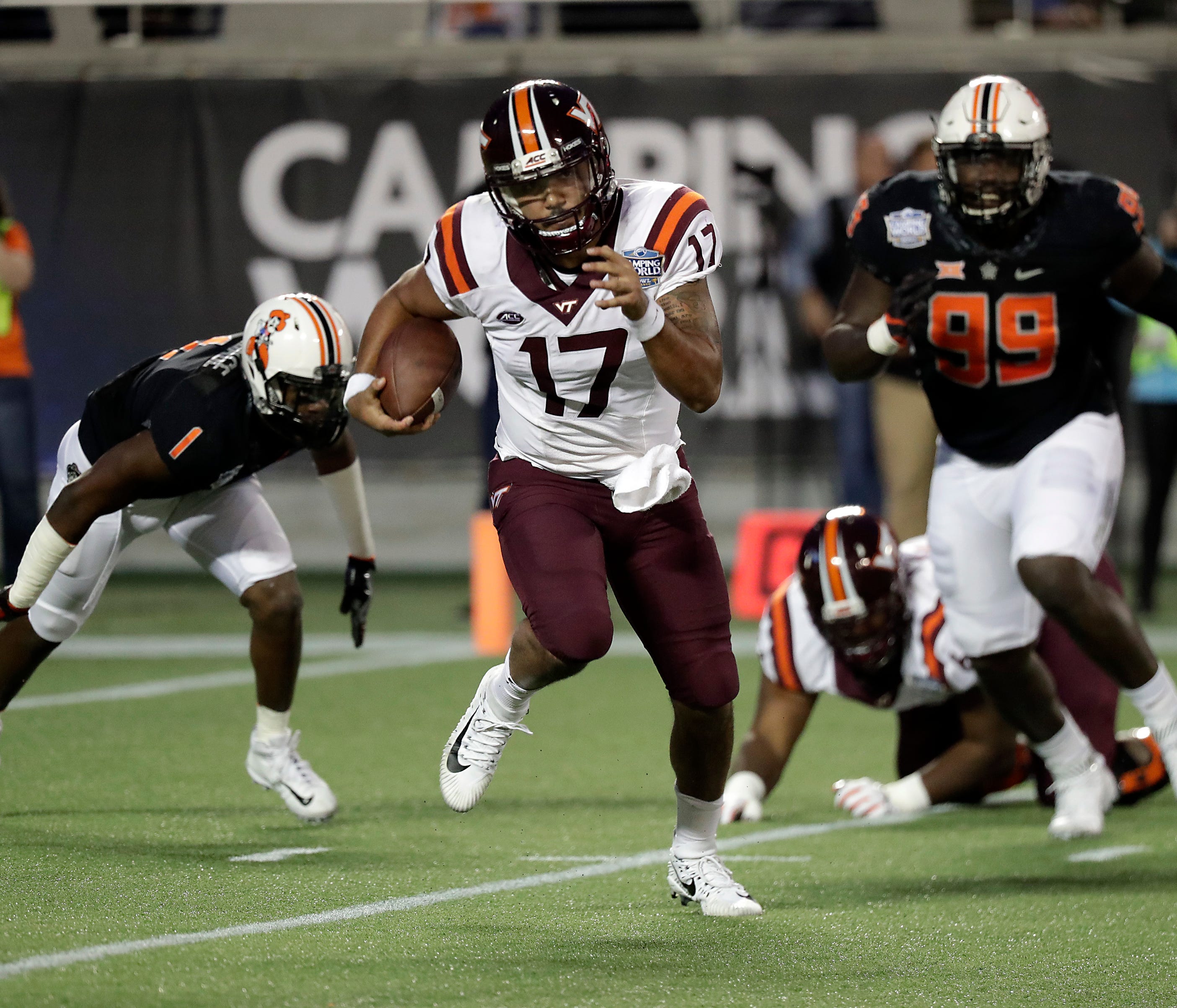 Virginia Tech quarterback Josh Jackson (17) scrambles away from Oklahoma State linebacker Calvin Bundage (1) and defensive end Trey Carter (99) during the first half of the Camping World Bowl NCAA college football game, Thursday, Dec. 28, 2017, in Or