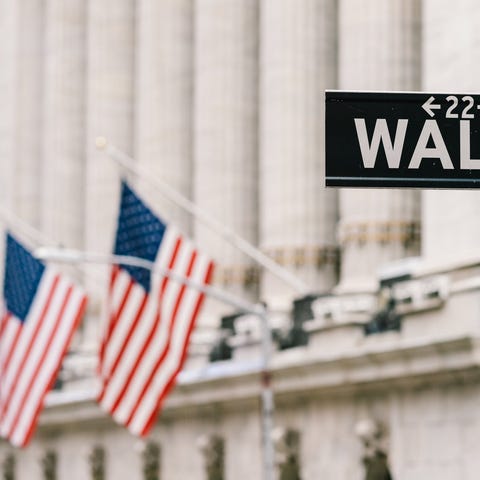 Wall Street sign post with American flags in the b