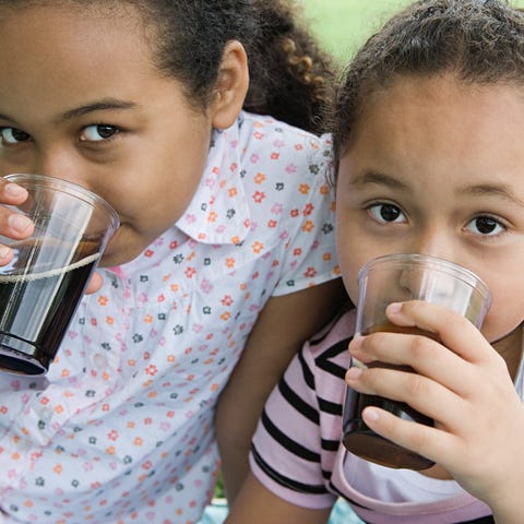 Two little girls drinking cola.