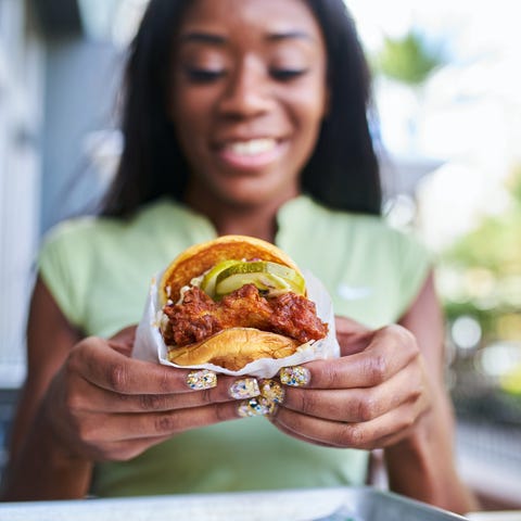 A person holds a fried chicken sandwich towards th