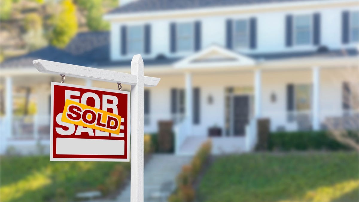 For Sale sign in front of a house with a sold sticker on it.