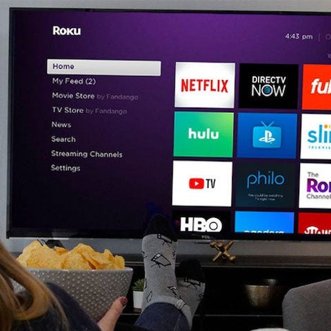 A person sitting on a couch in front of a Roku TV 